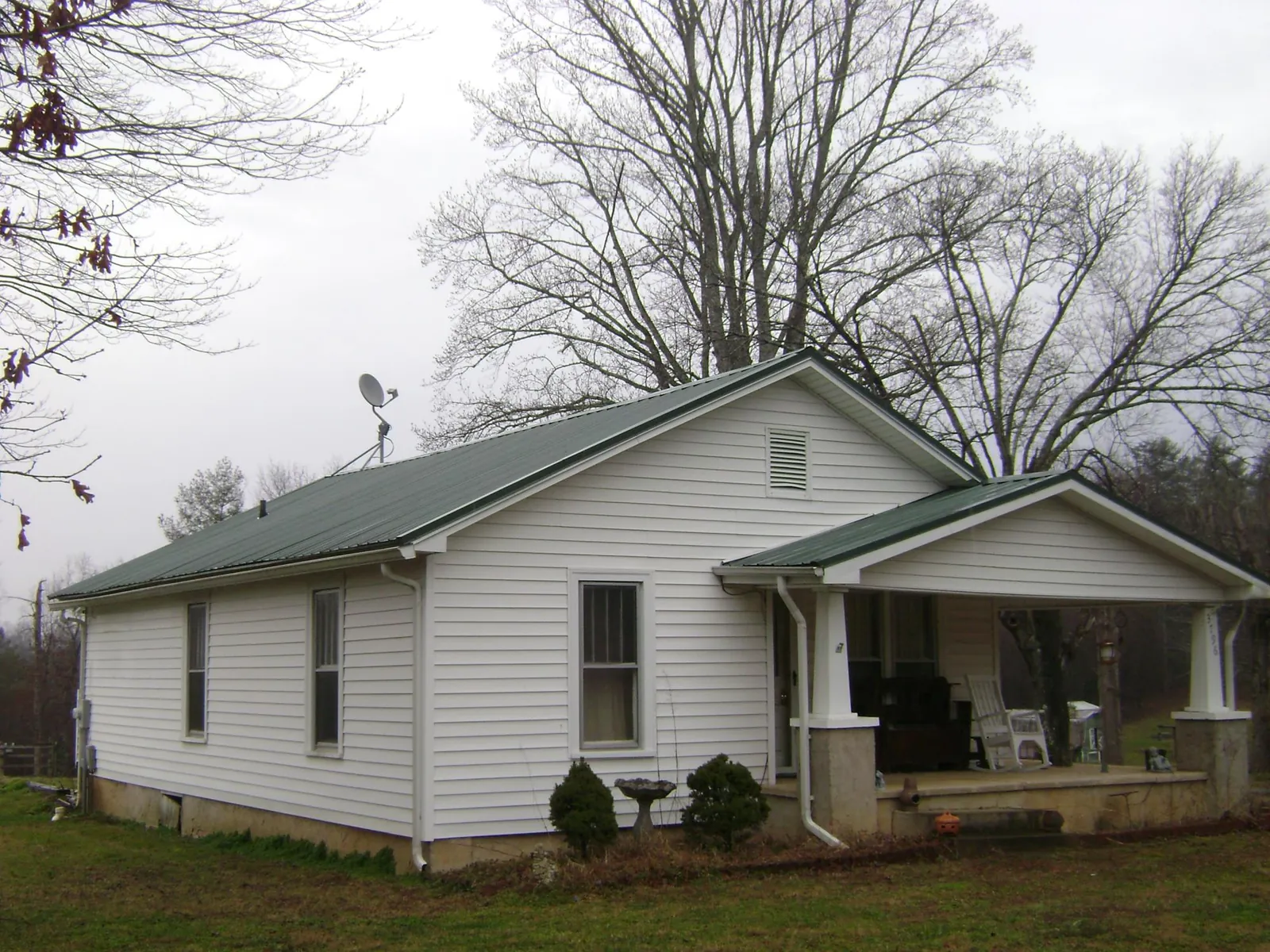 Green metal roof on a white bungalow with a side porch in Bradford